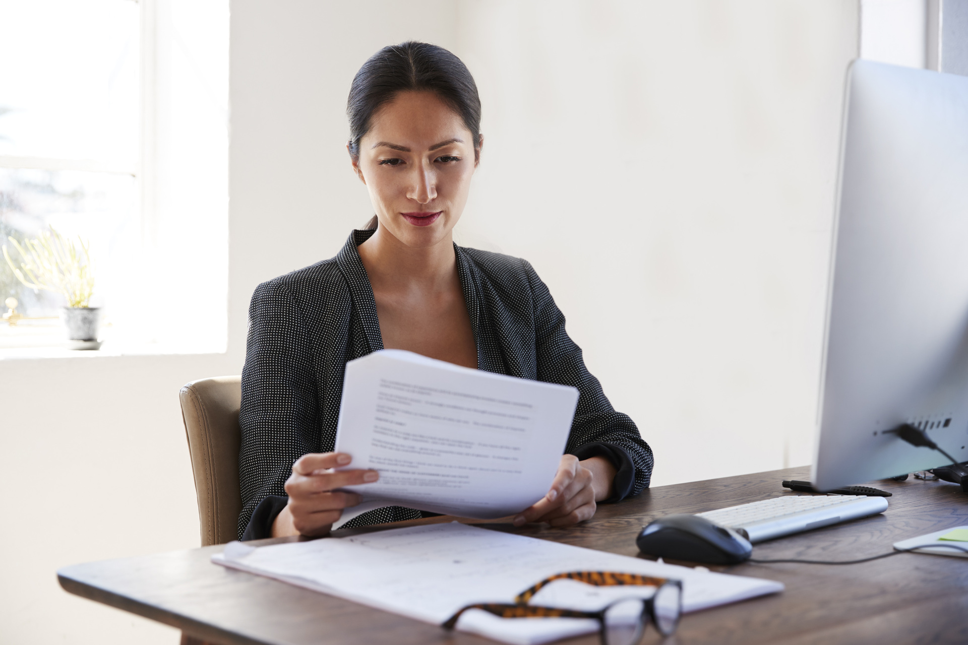 woman reading documents at her desk woman reading documents at her desk