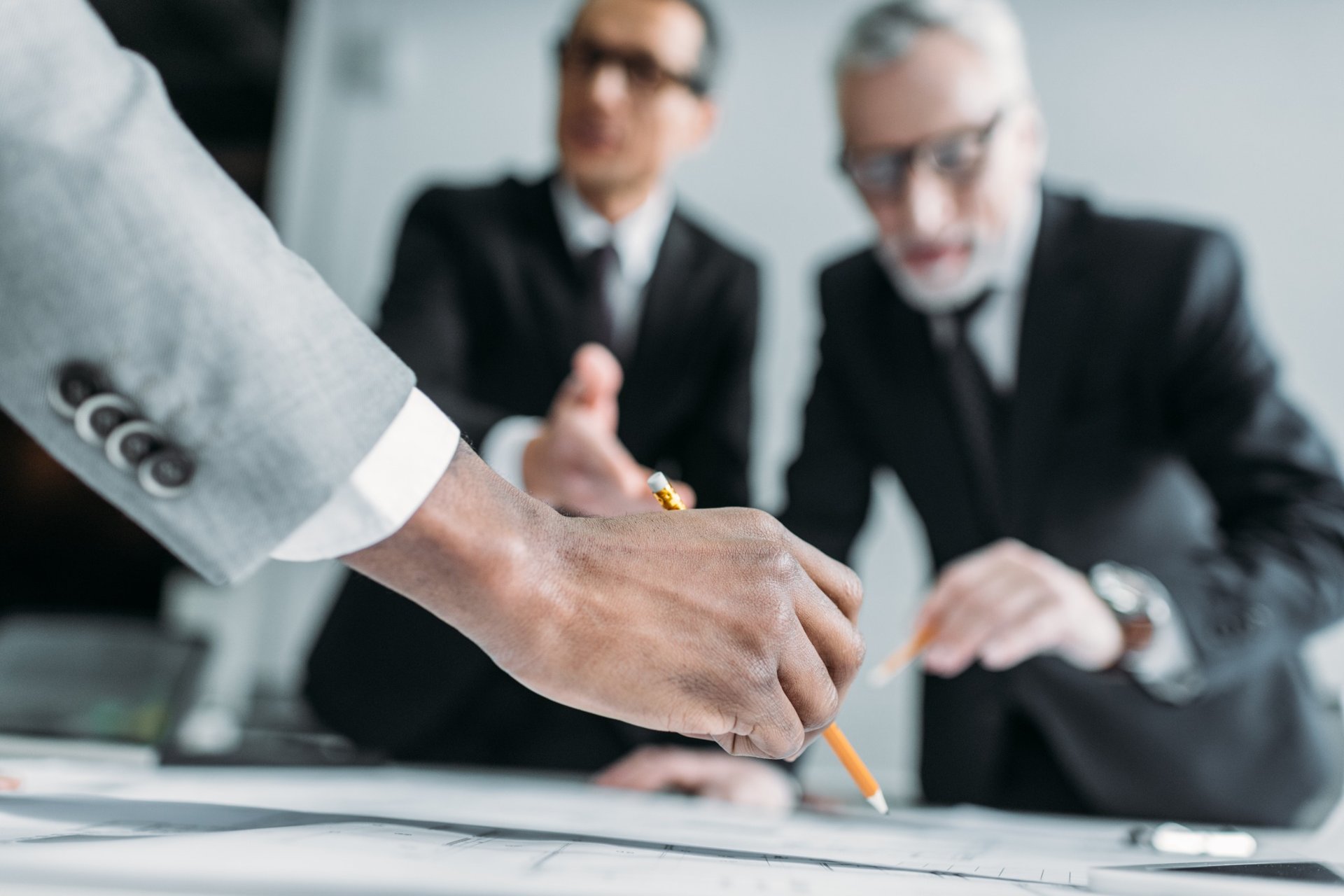 Close-up of business meeting with two suited men discussing documents Close-up of business meeting with two suited men discussing documents