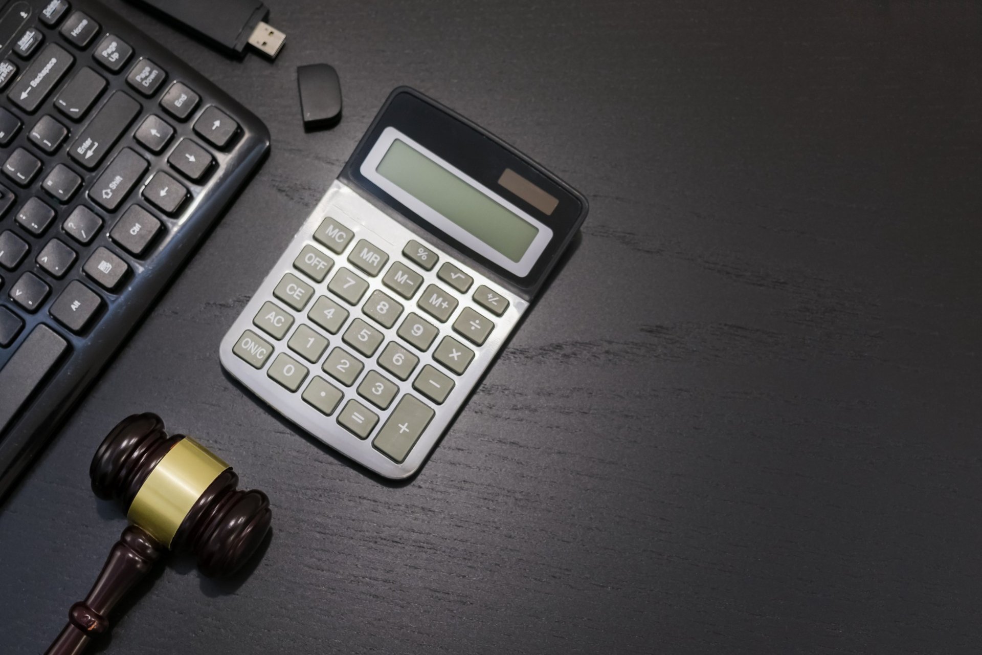 Gavel and calculator on lawyer's desk beside keyboard and flash drive Gavel and calculator on lawyer's desk beside keyboard and flash drive