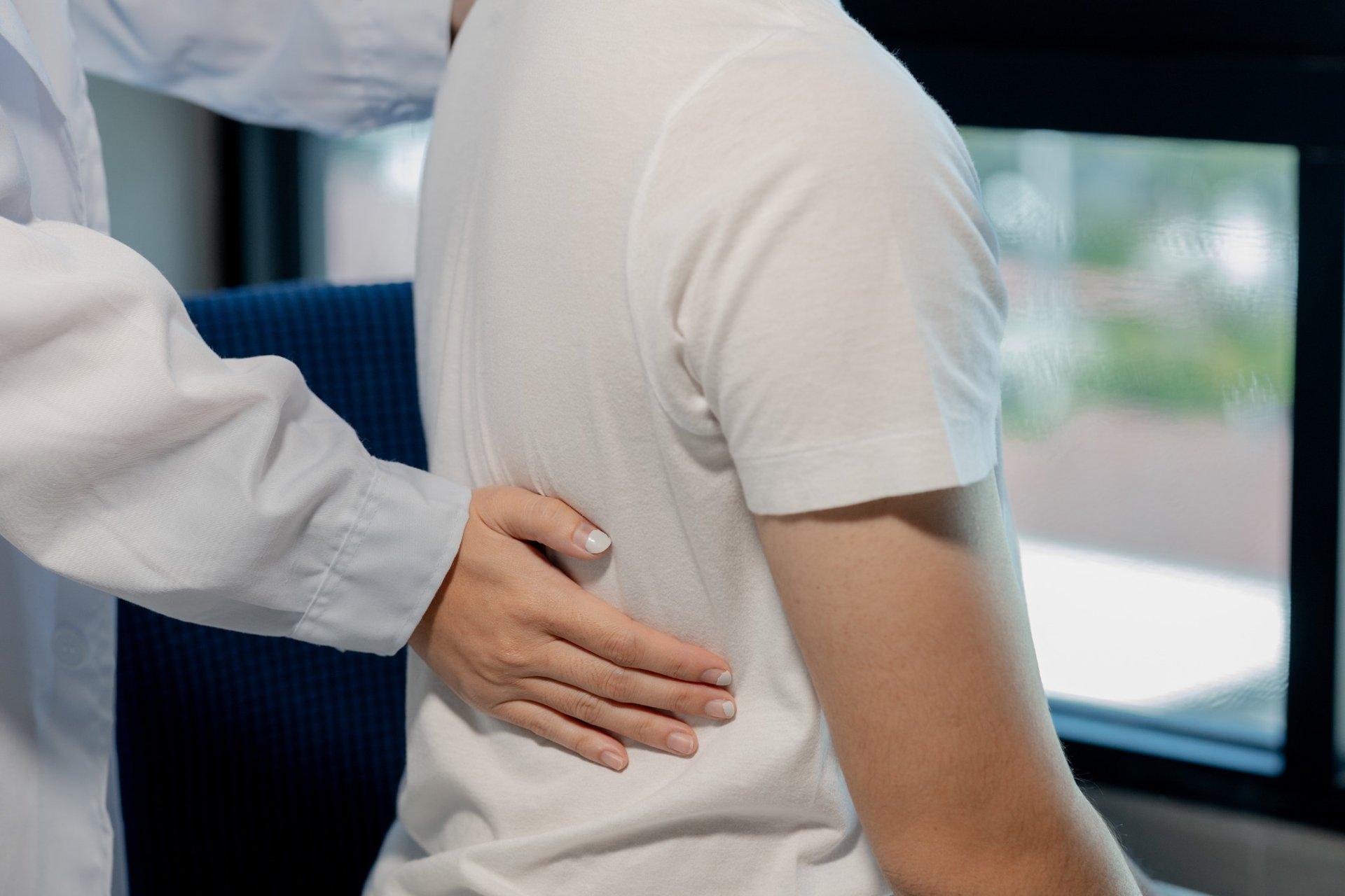 Physical therapist assisting patient with lower back pain treatment Physical therapist assisting patient with lower back pain treatment