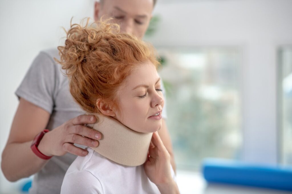 Physiotherapist adjusting a cervical collar for a young woman