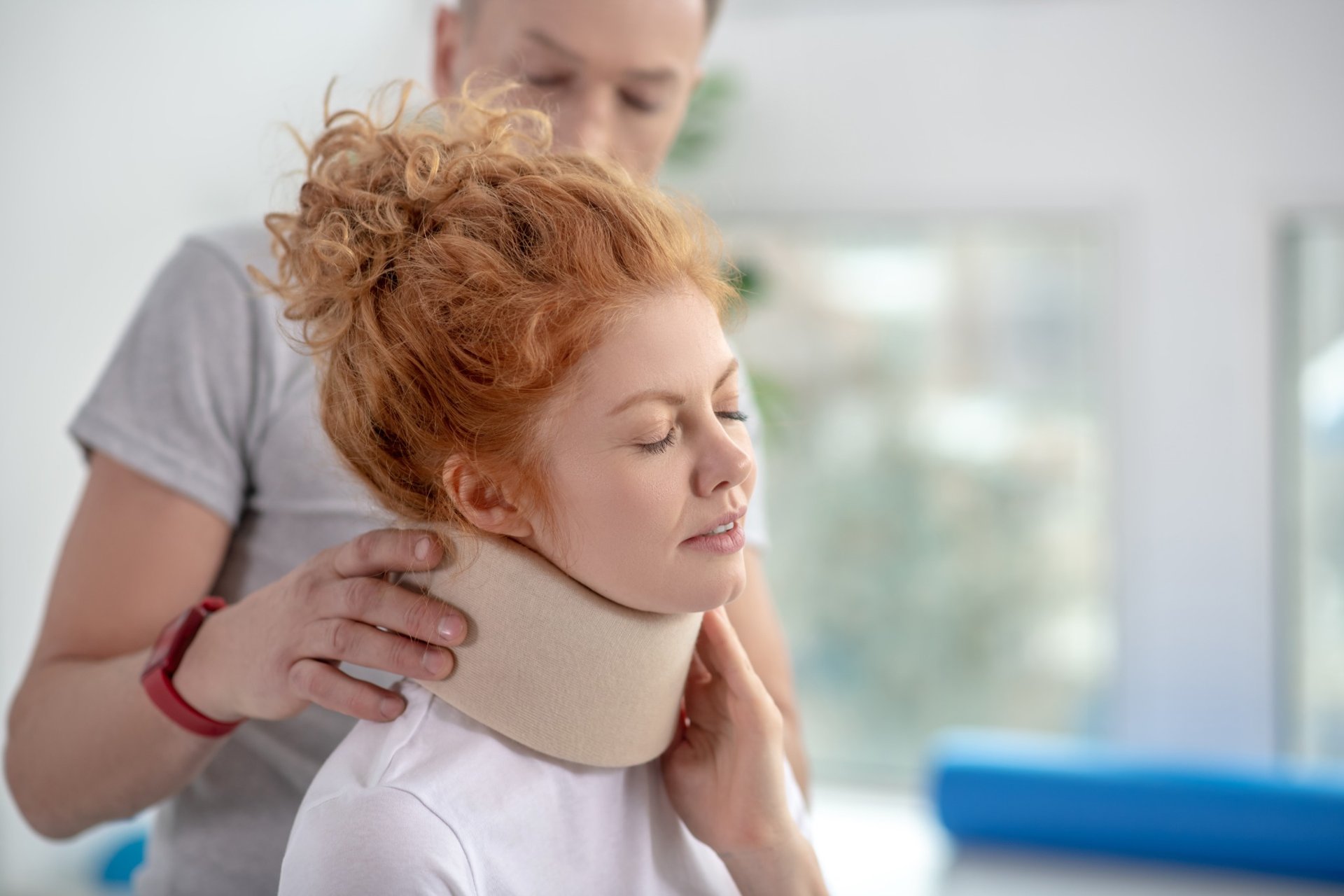 Physiotherapist adjusting a cervical collar for a young woman