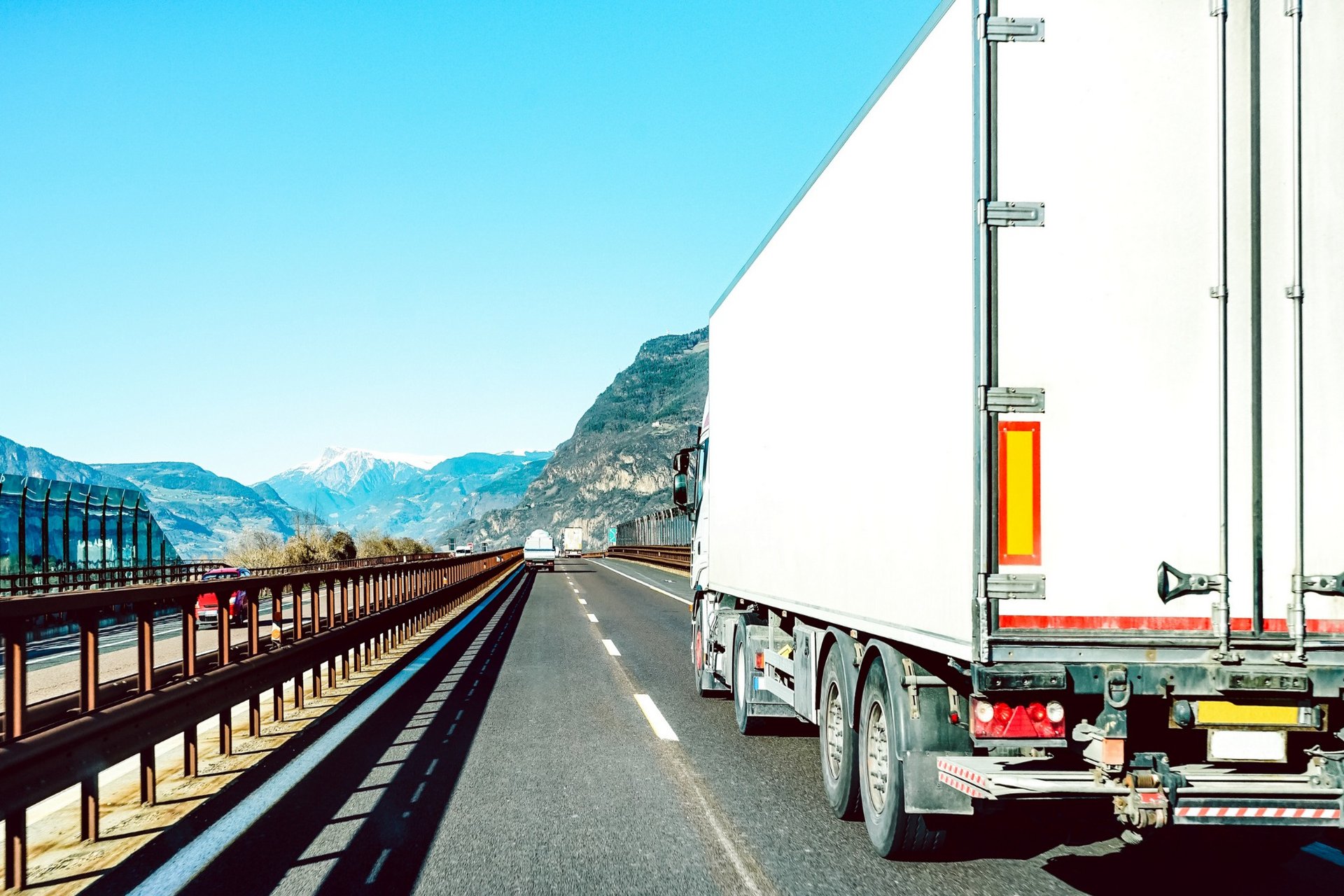 Semi-truck driving on highway with mountains in background
