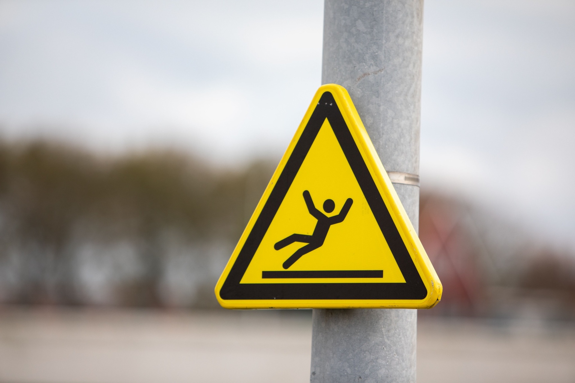Yellow caution sign warning of slippery surface on pole
