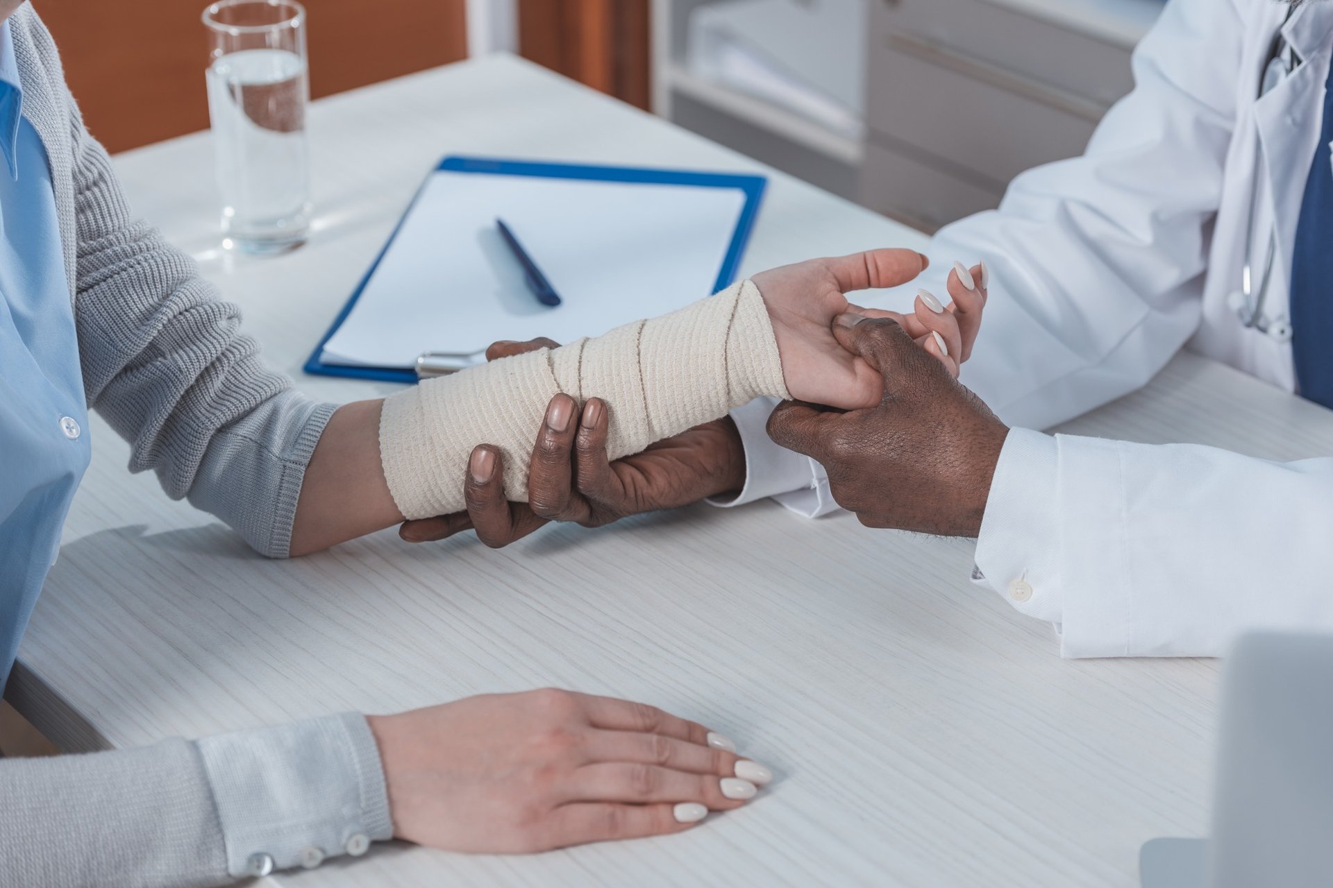 Doctor examining a patient’s injured wrist wrapped in a bandage