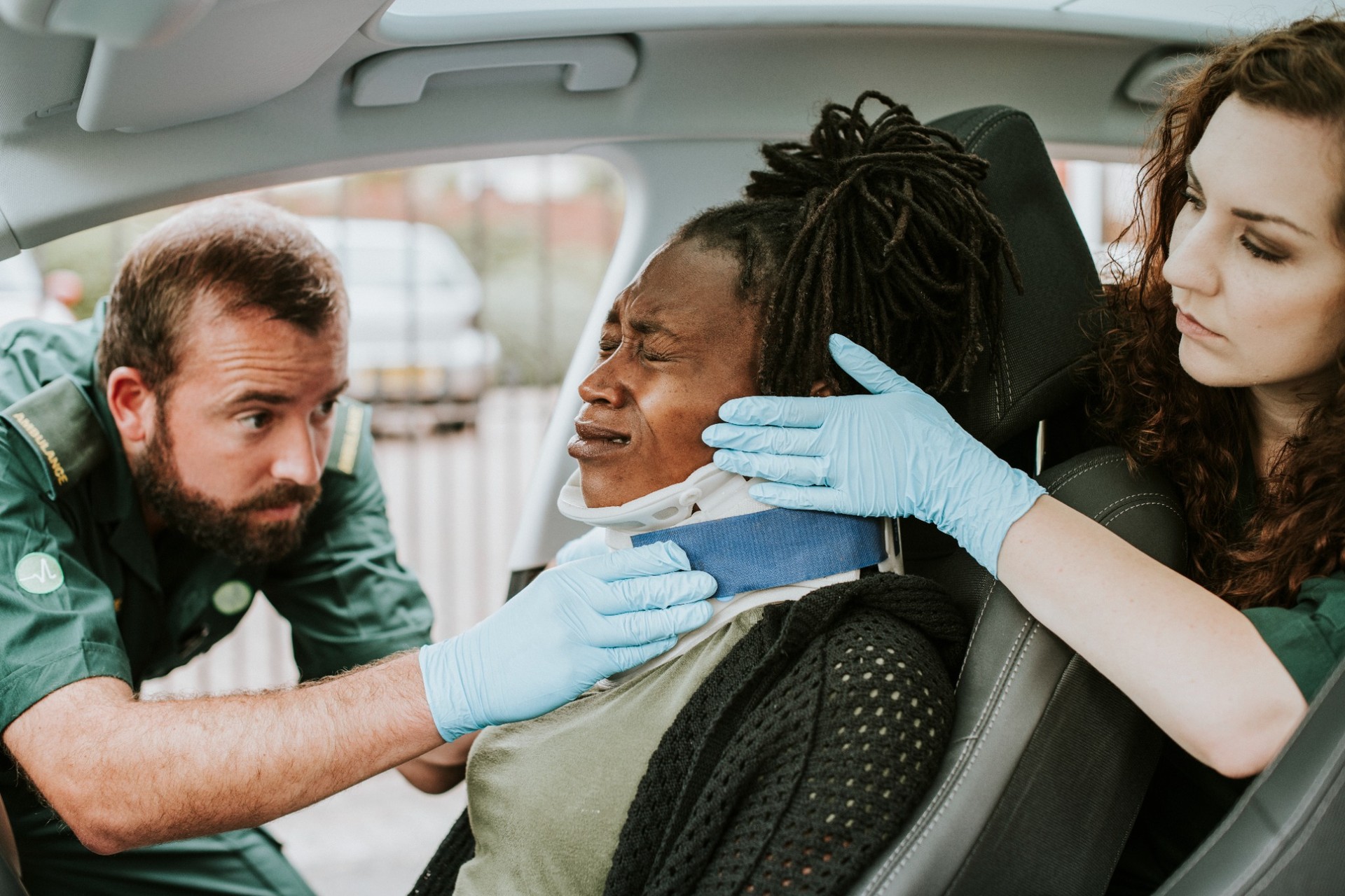 Emergency paramedics applying a cervical collar to an injured person in a car