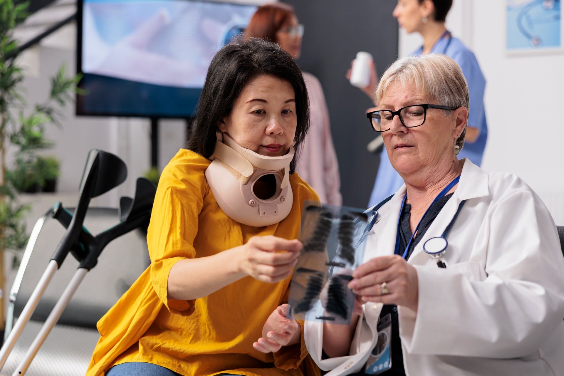 Female patient with a cervical collar reviewing X-ray with a senior doctor
