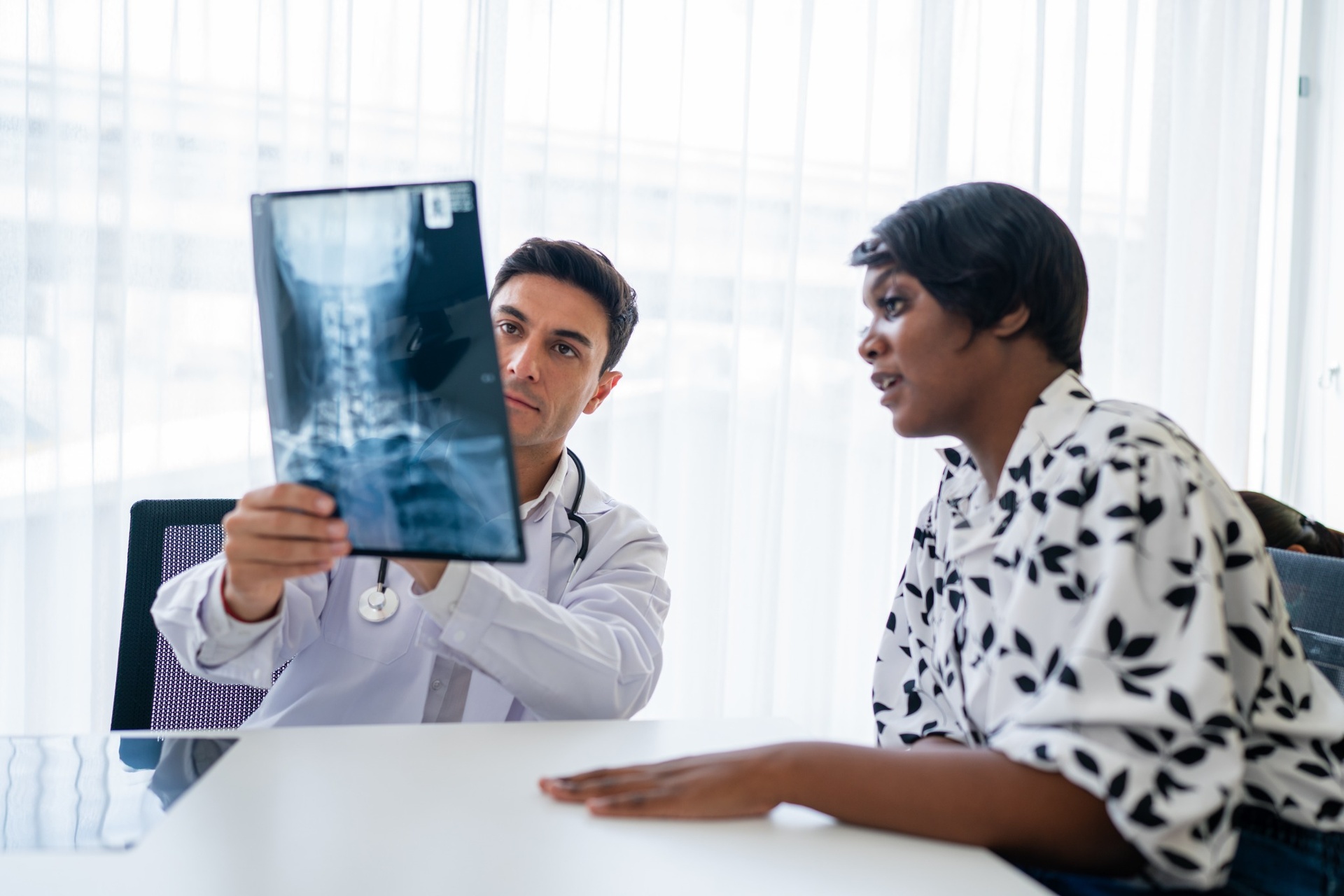 Male doctor showing and interpreting spinal X-ray results to a female patient