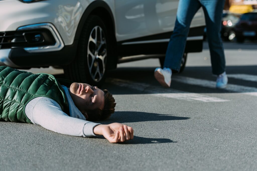 A woman running to victim of car accident lying on road