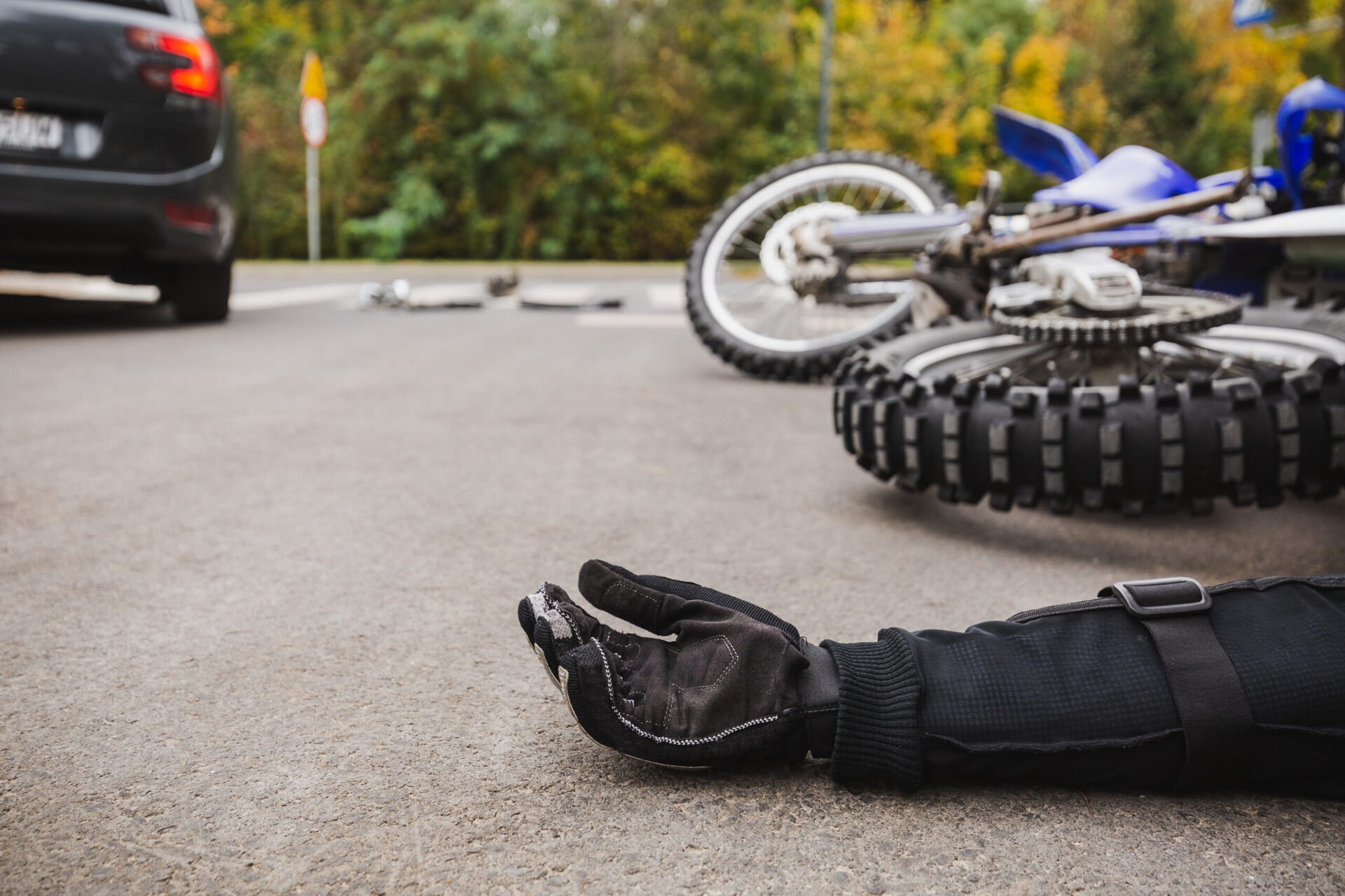 Motorcycle accident scene with rider’s arm on the ground and bike lying nearby