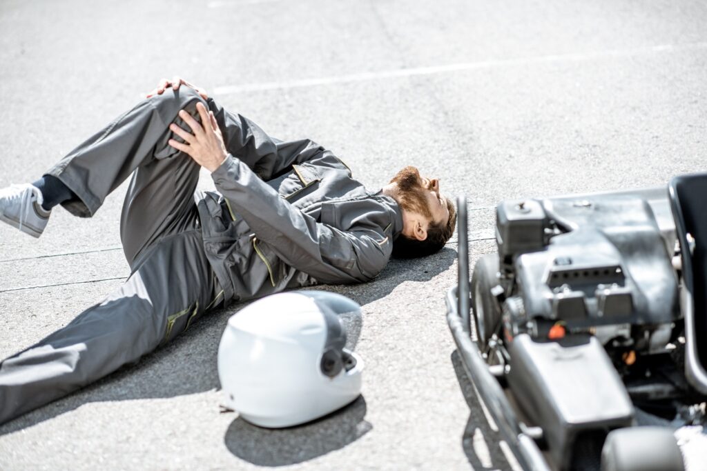 An injured man lies on the ground with his hands on his knee