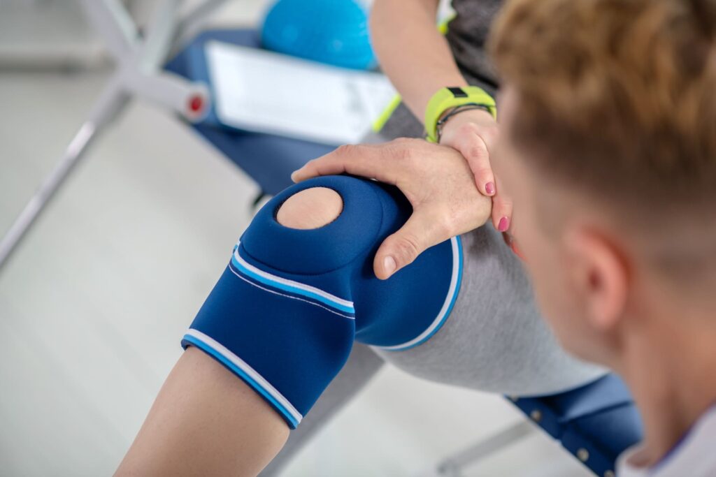 male physiotherapist hands examining knee bandage